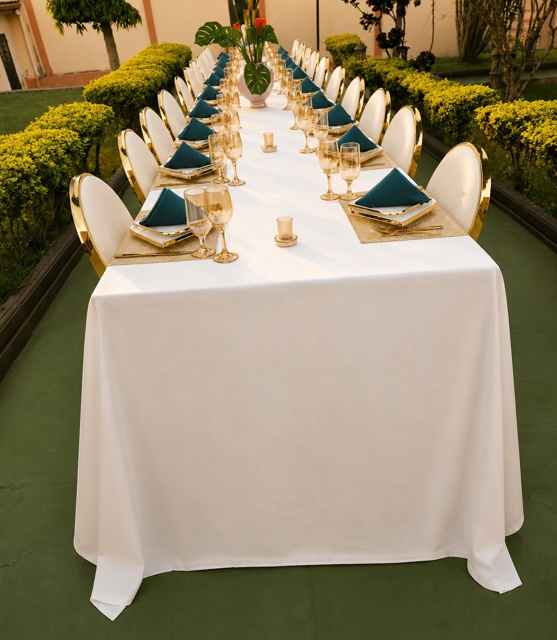 Table de banquet au jardin, chaises dorées et serviettes vert canard, à la tombée du jour